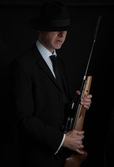 Portrait of a gangster like man holding a rifle