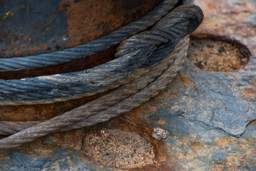 Fototapeta na wymiar A metal cable tied around a rusty bitt