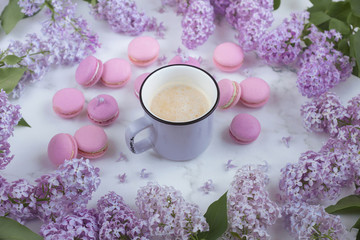 Fototapeta na wymiar Macaroons with coffee on a marble background with lilac flowers, Light background, Confectionery in a blogger style