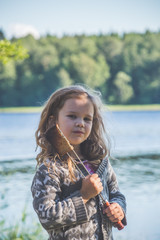 Fototapeta premium child on the lake in the woods eating fried bread in the campaign