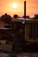 Fototapeta na wymiar Caterpillar Old Tractor in a Field during Sunset