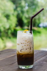 latte coffee and milk cold drink on the glass on wood table in the nature background