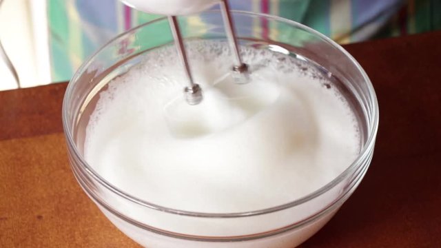 La cuoca in cucina monta l'albume per il dolce tiramis&ugrave;