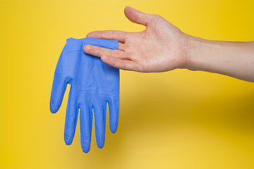 Doctor putting on sterile gloves isolated on yellow