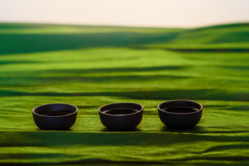 Obraz na płótnie Canvas Three cups of ceramics on the green background
