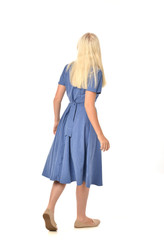 full length portrait of blonde girl wearing blue dress. standing pose with back to the camera. isolated on white  studio background.