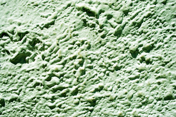 Wall with pastel green plaster imitating waves on water surface, grunge texture background