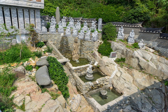 White stone carved statues of Chinese Buddha, priests and many animals on the artificial waterfall at Haedong Yonggungsa Temple in Busan, South Korea.