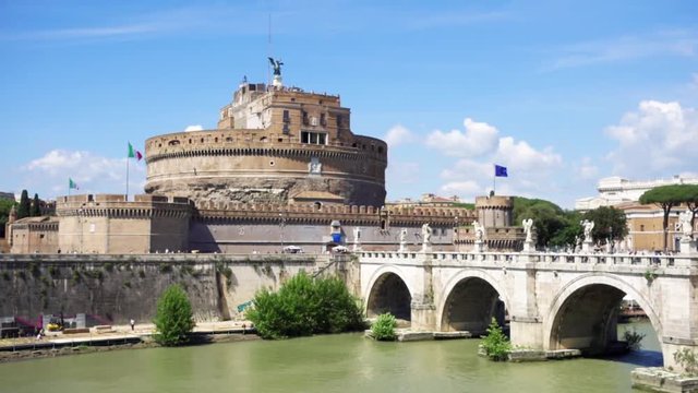 View of medieval St. Angelo castle from the other side of Tiber river. Castello Sant'Angelo fortress and bridge on sunny day in Rome, Italy in slow motion