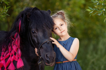 Cute little girl and pony in a beautiful park