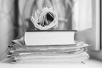 Rolled newspapers and pile of books. Fresh daily papers with news and business literature. Concept...