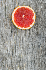 Fototapeta na wymiar Pink ripe grapefruit slice on old wooden background