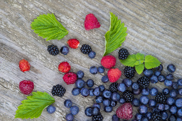 mix of blueberries, blackberries, raspberries on old wooden table background