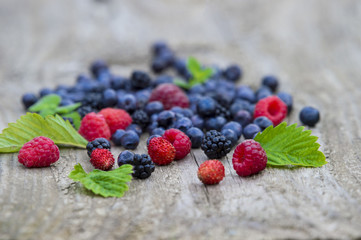 mix of blueberries, blackberries, raspberries on old wooden table background