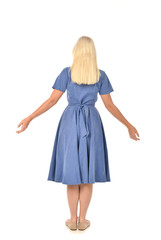 full length portrait of blonde girl wearing blue dress. standing pose with back to the camera. isolated on white  studio background.