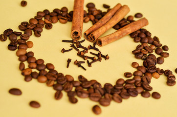 coffee beans in a circle with cinnamon and clove on a yellow background with a place under the text