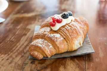 Croissant filled with mascarpone and garnished with cranberries and currants