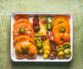 Colorful sliced tomatoes grown in the garden on white tray, top view. The concept of natural vegetables, healthy eating and clean food.