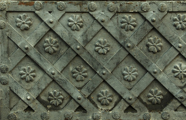 Ancient forged metal texture with decorative overlays. Doors, gates, shutters. Detail of a medieval gray door with metal decoration, background, close-up.