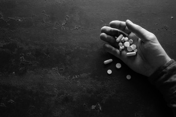 hand with pills on a black background with space for text concept stop suicide