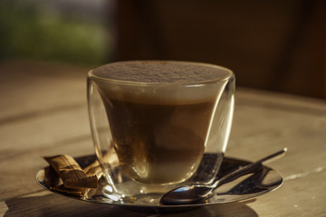 Hot chocolate with cinnamon and whipped cream on a wooden table. Chocolate is hot on the table.

