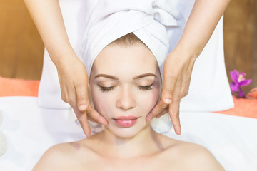 Fototapeta na wymiar beautiful girl enjoys face massage in spa salon. Procedures for beauty and rejuvenation. Thai massage