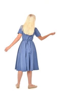 Full Length Portrait Of Blonde Girl Wearing Blue Dress. Standing Pose With Back To The Camera. Isolated On White  Studio Background.