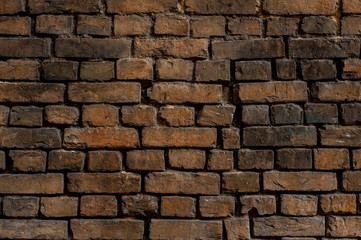 Old brown brick exterior wall with dark spots