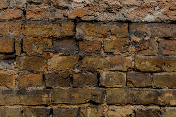 Old shabby brown brick exterior wall with dark spots