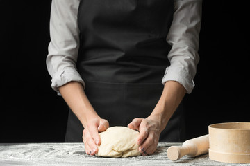 Chef cooking on a dark wooden background. The concept of nutrition, cooking pasta, pizza, and bakery