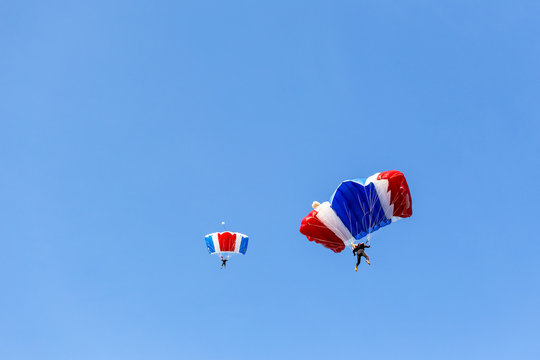 skydiver team in colorful parachute gliding after free fall jump with blue sky background