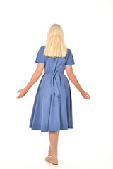 full length portrait of blonde girl wearing blue dress. standing pose with back to the camera. isolated on white  studio background.