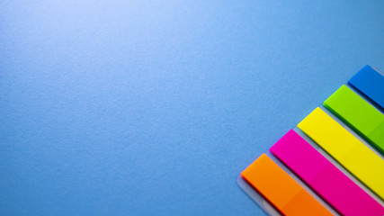 Multicolored bookmarks on blue background. View from above with copy space