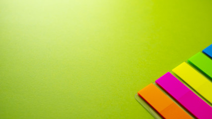 Multicolored bookmarks on green background. View from above with copy space