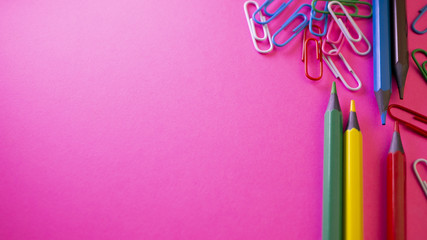 Pencils and paper clips on the table. School supplies on pink background. View from above with copy space