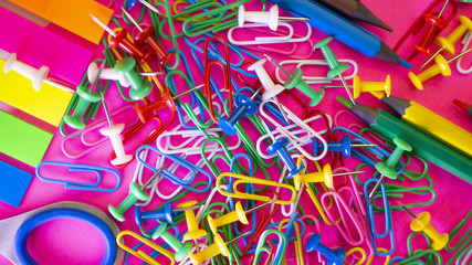 School supplies on pink background. Pens, pencils, scissors, paper clips and a marker on the table. View from above with copy space