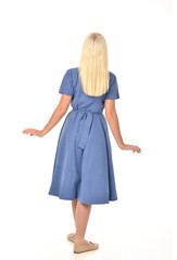 full length portrait of blonde girl wearing blue dress. standing pose with back to the camera. isolated on white  studio background.