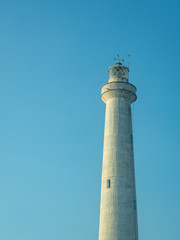 A white lighthouse set against a blue sky in the summer