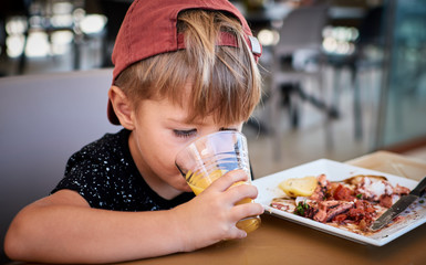 Little boy eating healthy Mediterranean food - octopus and orange juice
