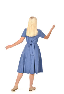 Full Length Portrait Of Blonde Girl Wearing Blue Dress. Standing Pose With Back To The Camera. Isolated On White  Studio Background.