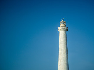 A white lighthouse set against a blue sky in the summer