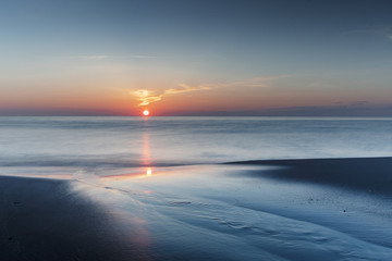 Ocean water and sand texture with reflection at colorful sunset. Danish Coastline. Lonstrup in North Jutland in Denmark, Skagerrak, North Sea