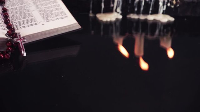 Open Holy Bible and candles on an old wooden burnt table. Beautiful dark background. Religious concept.