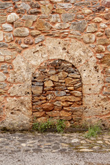 Bricked up and blocked doorway in an old stone building with arch over door frame