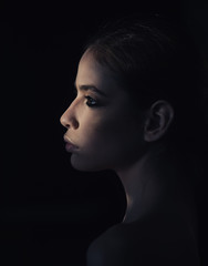 Face of pretty woman with make up in darkness. She is mystery for you. Mysterious girl hiding from day light. Portrait calm face mysterious confident lady on black background