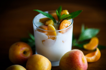 homemade yogurt with ripe apricots on wooden table