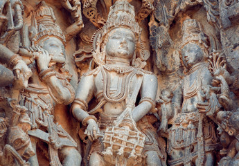 Fototapeta na wymiar Fragment of stone carved relief with musicians playing music of gods. 12th century South Indian temple. Halebidu heritage, India