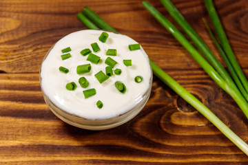 Sour cream and green onion on wooden table