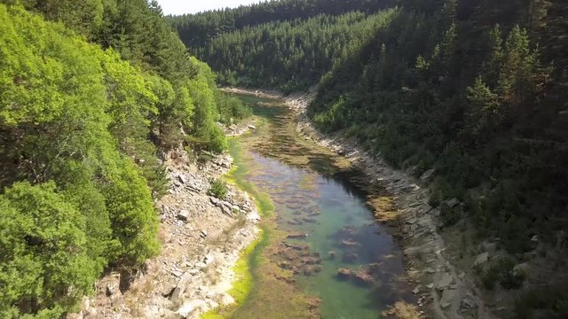 Aerial drone view flying over a long, narrow lake located in a tree lined canyon in Wales