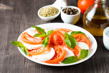 Close-up photo of caprese salad with ripe tomatoes, basil, buffalo mozzarella cheese. Italian and Mediterranean food concept. Fresh and healthy organic meal. Starter and antipasti. 